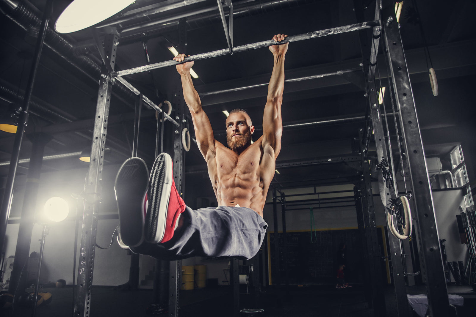 Muscular man performing a hanging exercise on gym rings.