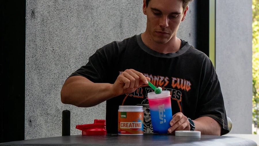 A person mixing a colorful drink in a clear cup.