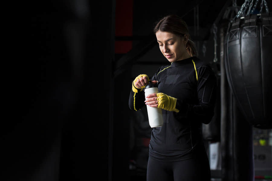 Athlete in workout gear mixing a protein shake.