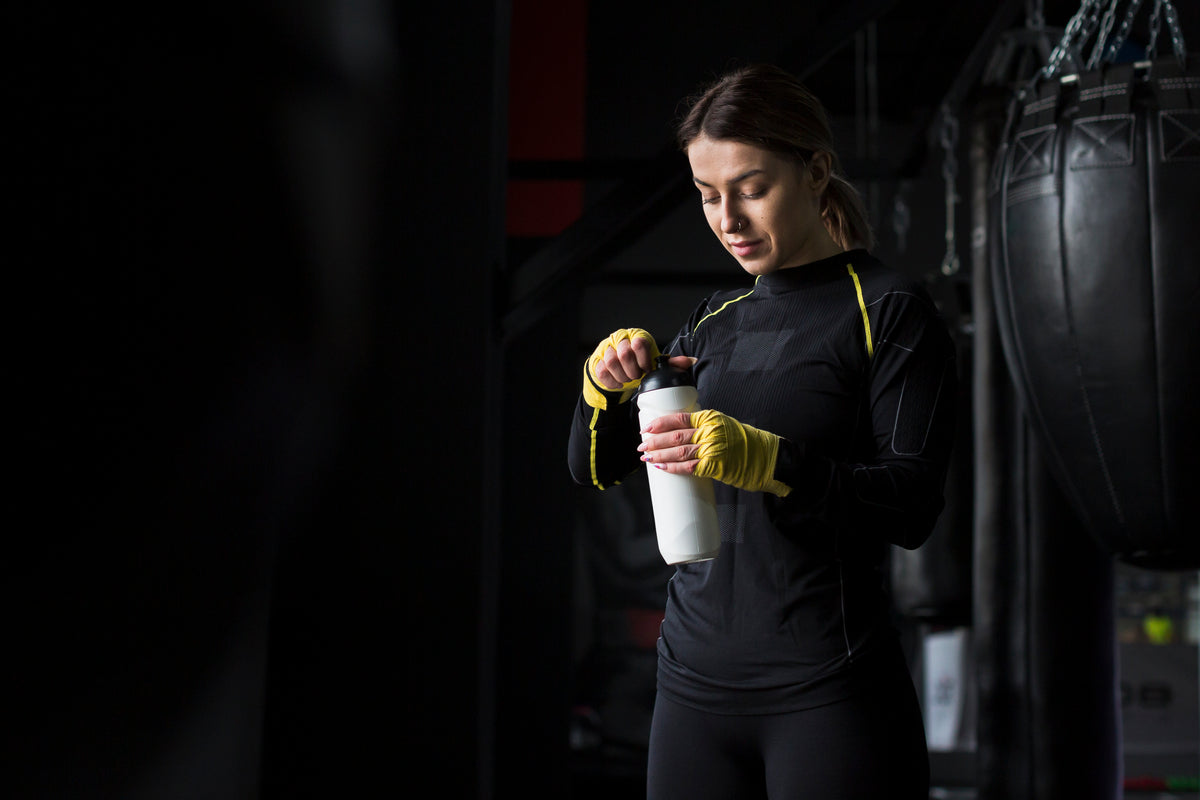 Athlete in workout gear mixing a protein shake.