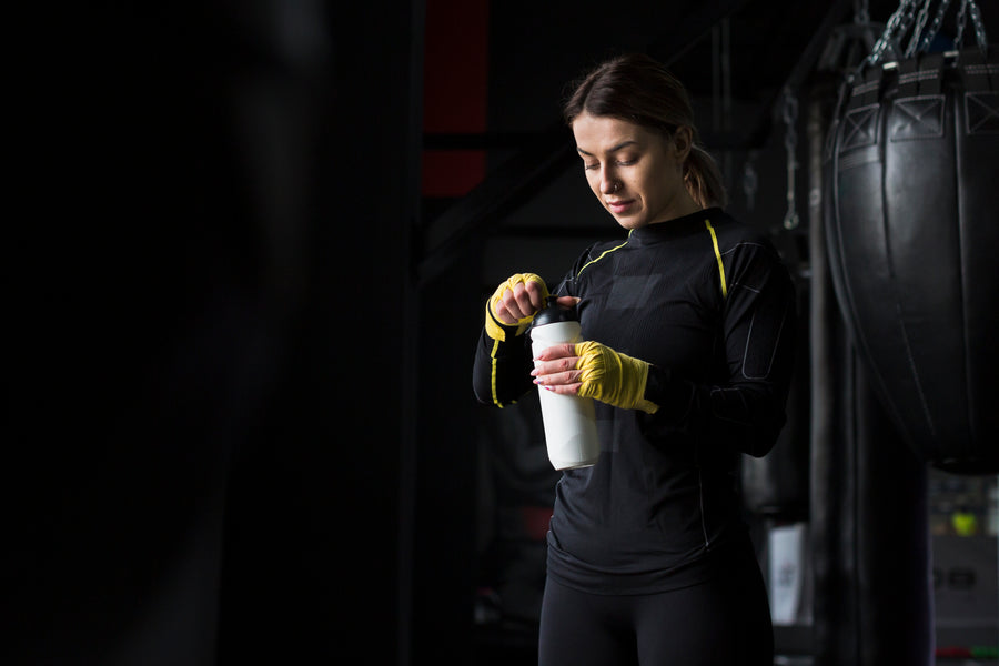 Athlete in workout gear mixing a protein shake.