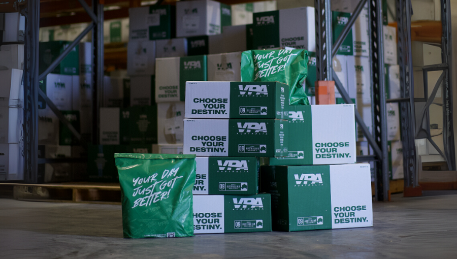Stacked green and white packaging boxes in a warehouse setting.