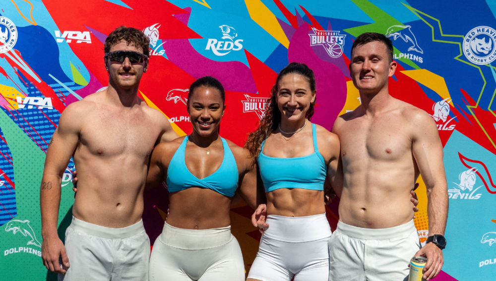 Group of four fit individuals posing against a colorful background.